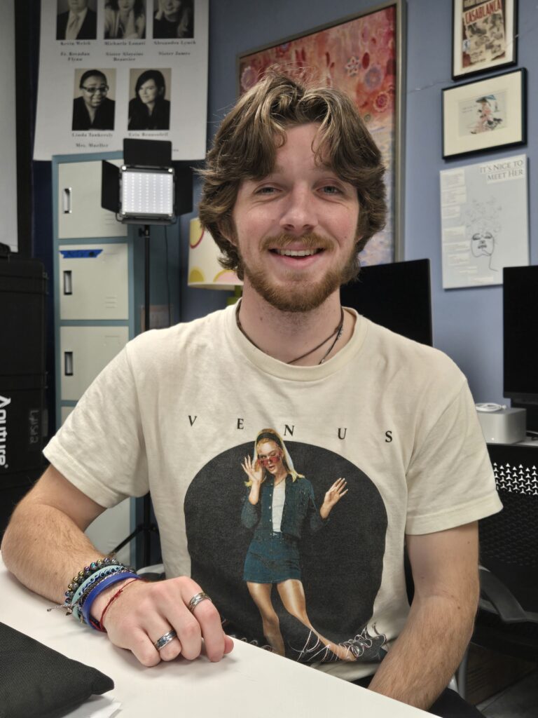 College student sitting at a table, with one arm on the table.